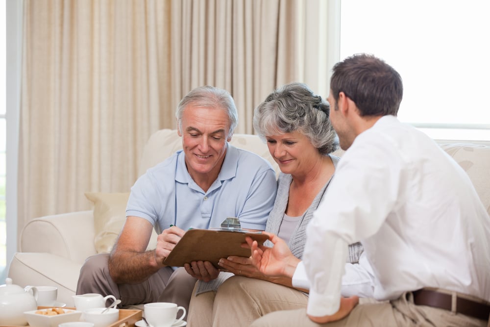 Older couple reviewing their life insurance coverage with an insurance professional. Older couple reviewing their life insurance coverage with an insurance professional.