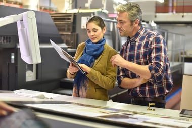 Two manufacturing business owners reviewing production plans inside their facility.